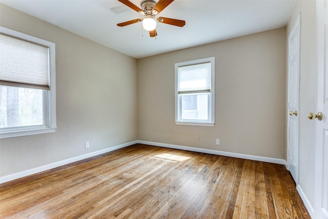 unfurnished room featuring plenty of natural light, wood finished floors, and baseboards