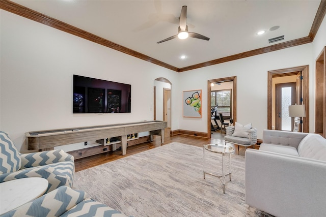 living area featuring arched walkways, visible vents, crown molding, and wood finished floors