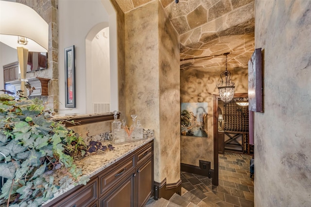 bathroom with stone finish flooring, visible vents, and vanity