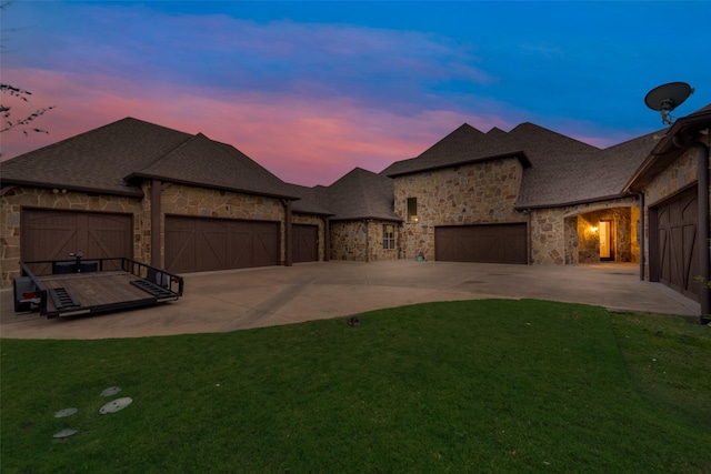 view of front of house with driveway, a yard, a garage, and stone siding