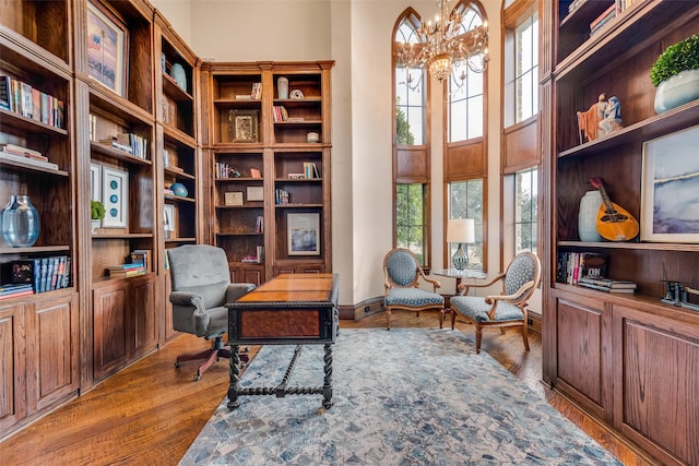 office space with wood finished floors, a chandelier, and a towering ceiling