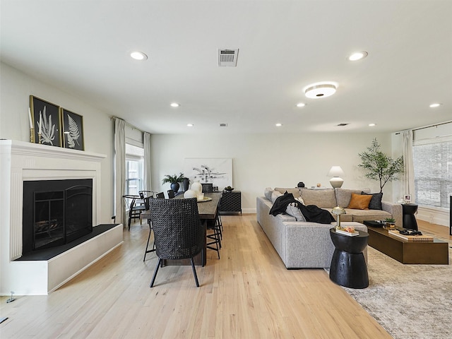 living room featuring light wood-style floors, recessed lighting, a fireplace with raised hearth, and visible vents