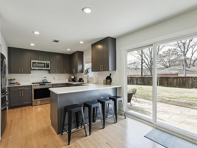 kitchen with a wealth of natural light, visible vents, a peninsula, and stainless steel appliances