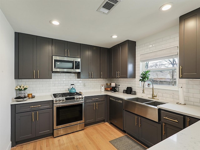 kitchen featuring visible vents, light wood-type flooring, light countertops, stainless steel appliances, and a sink