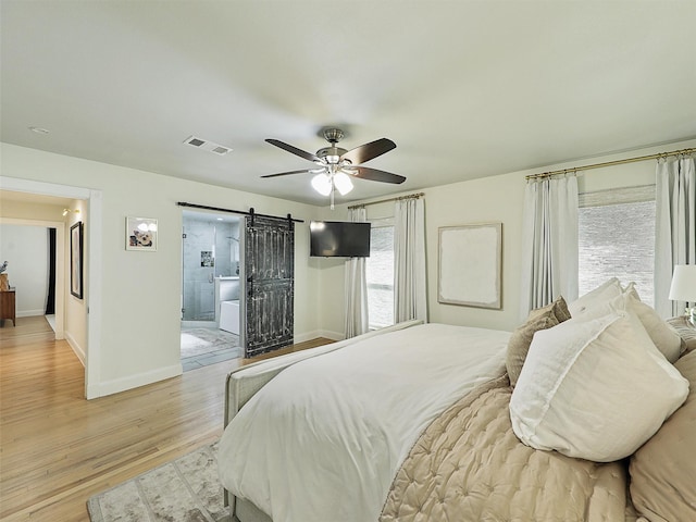 bedroom featuring light wood finished floors, visible vents, multiple windows, and a barn door