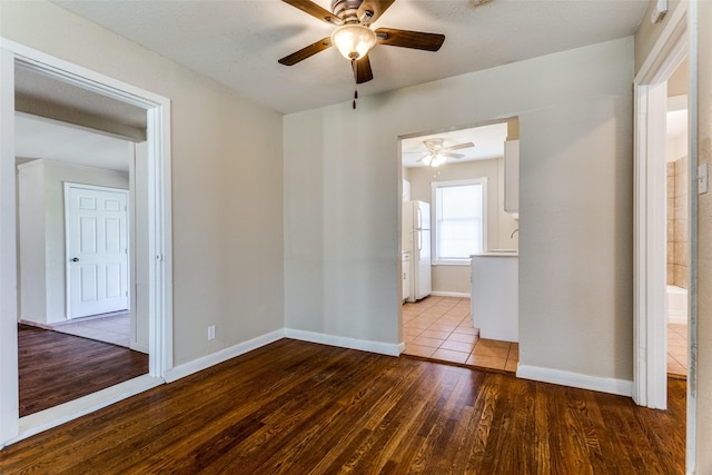 spare room featuring baseboards, wood finished floors, and a ceiling fan