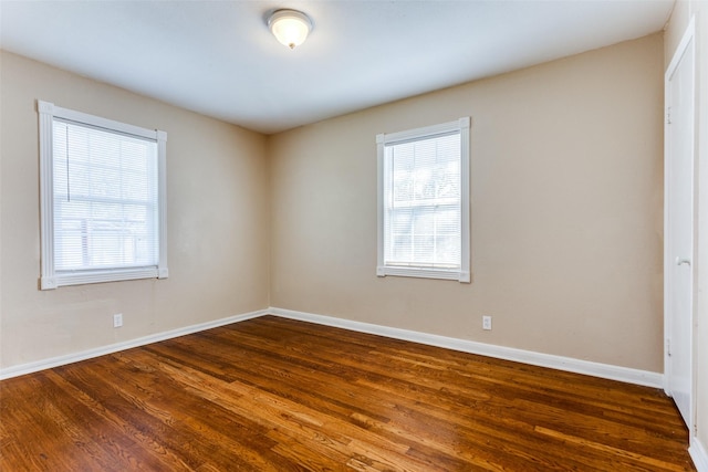 unfurnished room with baseboards and dark wood-style flooring