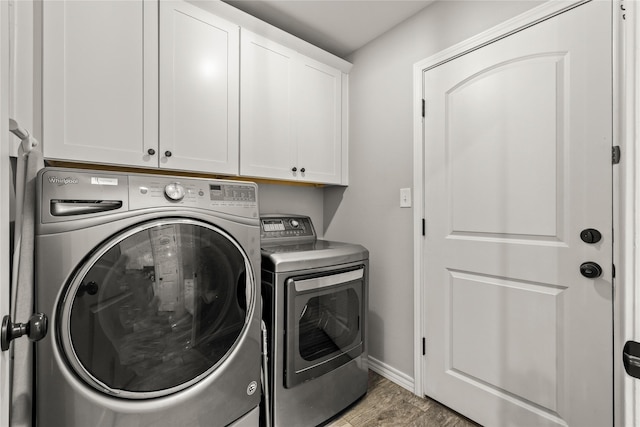 clothes washing area with cabinet space, washer and dryer, baseboards, and wood finished floors