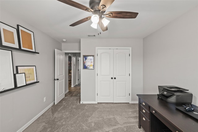 office space with a ceiling fan, light colored carpet, visible vents, and baseboards