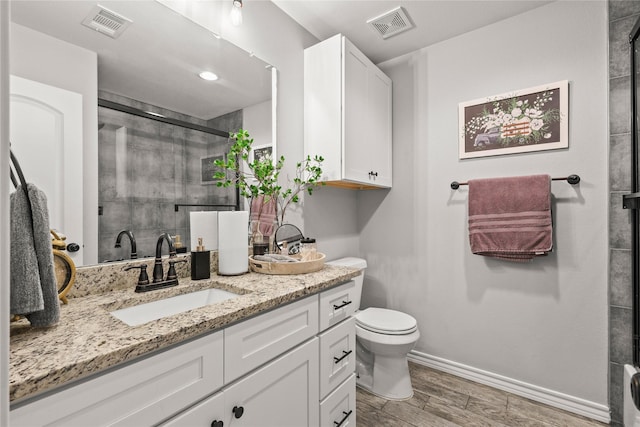 bathroom featuring visible vents, vanity, toilet, and a shower stall