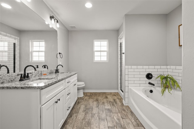 full bath with a healthy amount of sunlight, wood finished floors, and a sink