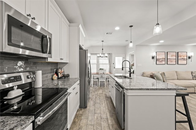 kitchen with light wood-type flooring, visible vents, a sink, backsplash, and appliances with stainless steel finishes