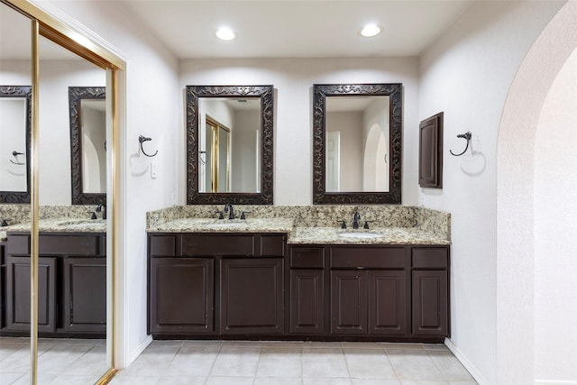 full bath with double vanity, tile patterned flooring, and a sink