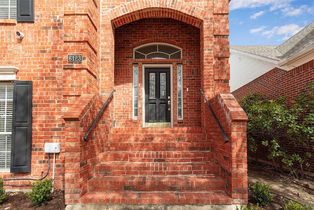 view of exterior entry featuring brick siding