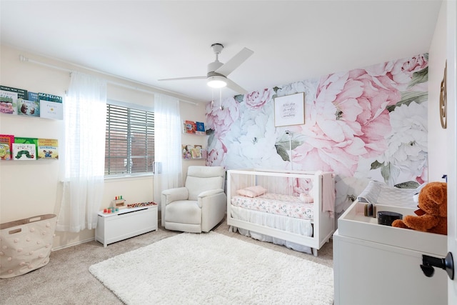 bedroom featuring carpet flooring, a nursery area, wallpapered walls, and ceiling fan