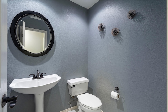 half bath featuring toilet and a textured wall