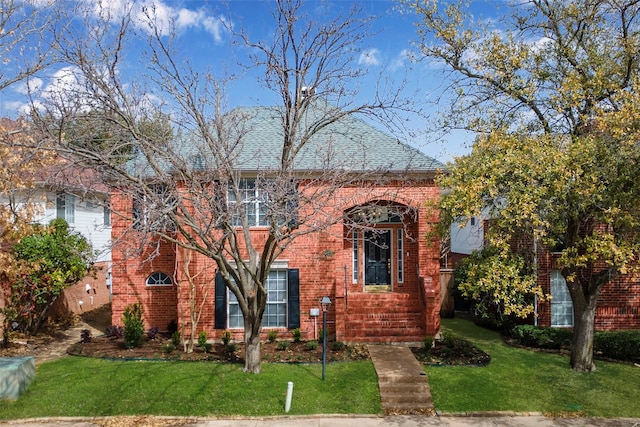 view of front of house featuring brick siding, roof with shingles, and a front lawn