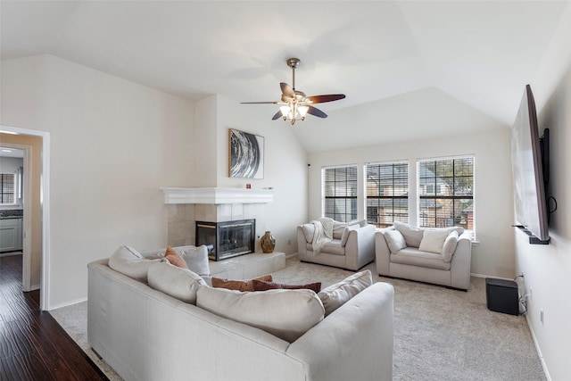 living area featuring ceiling fan, a tile fireplace, baseboards, and vaulted ceiling