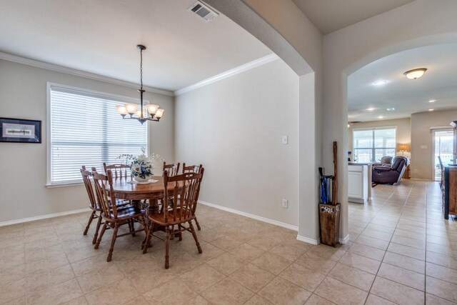 dining space featuring crown molding, visible vents, arched walkways, and baseboards