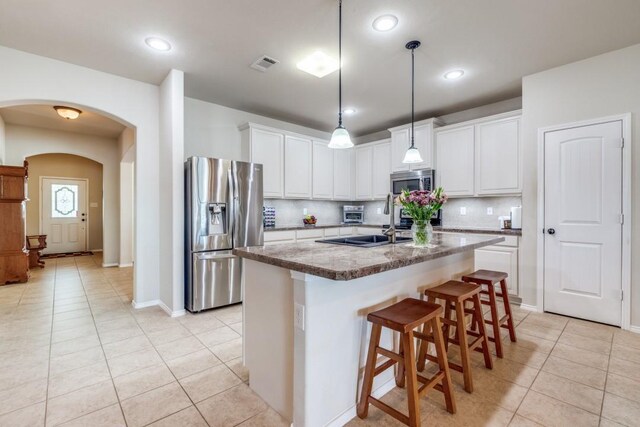 kitchen with visible vents, stainless steel appliances, arched walkways, white cabinets, and light tile patterned floors