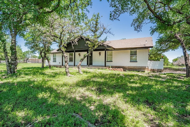 rear view of property with brick siding, a lawn, and fence