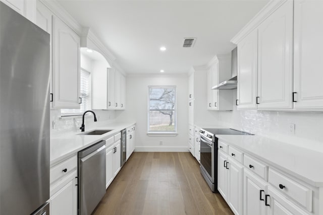 kitchen featuring visible vents, stainless steel appliances, wood finished floors, white cabinetry, and a sink