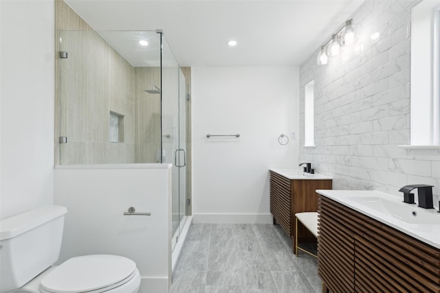 bathroom with a shower stall, toilet, two vanities, tile walls, and a sink