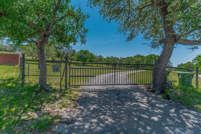 view of gate featuring fence and a lawn