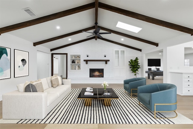 living room with visible vents, a brick fireplace, lofted ceiling with skylight, wood finished floors, and a ceiling fan