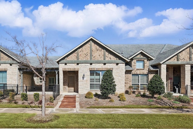 view of front of home featuring brick siding, roof with shingles, and fence