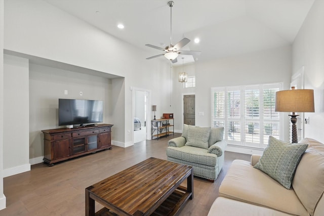 living area with baseboards, ceiling fan, recessed lighting, a high ceiling, and wood finished floors