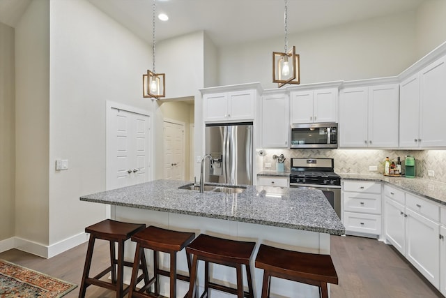 kitchen featuring decorative backsplash, dark wood finished floors, appliances with stainless steel finishes, and a sink