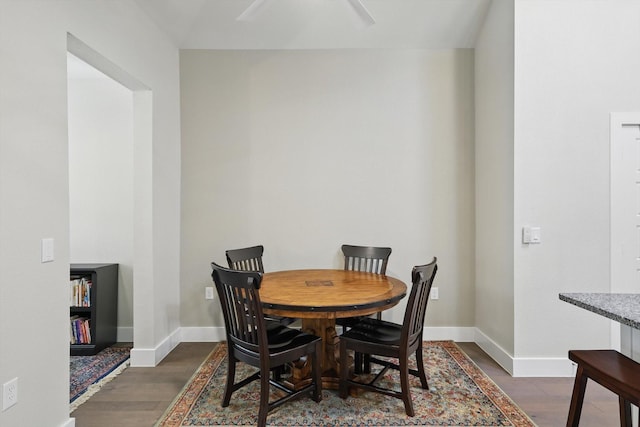 dining room with dark wood finished floors, ceiling fan, and baseboards