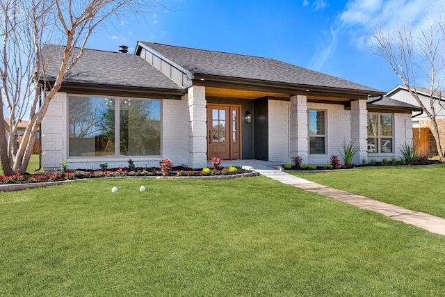 view of front of property featuring brick siding, a shingled roof, and a front yard