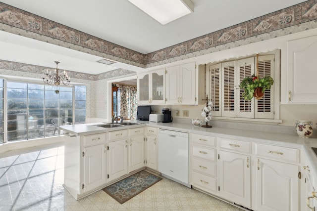 kitchen with light floors, wallpapered walls, a peninsula, a sink, and dishwasher