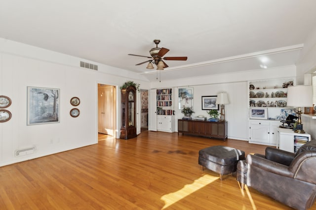 unfurnished living room featuring visible vents, light wood-style flooring, a ceiling fan, and built in features