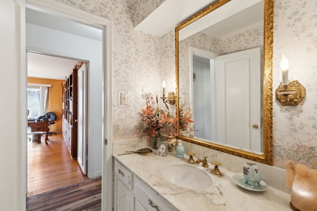 bathroom featuring wood finished floors, vanity, and wallpapered walls