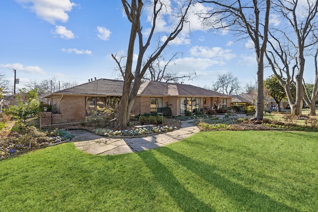 rear view of house featuring a lawn and brick siding