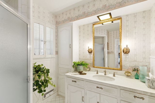 full bathroom with a shower with shower door, vanity, and wallpapered walls