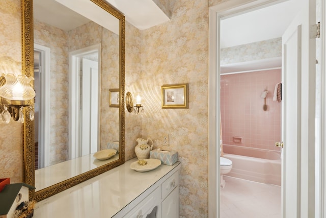 bathroom with toilet, wallpapered walls, and vanity