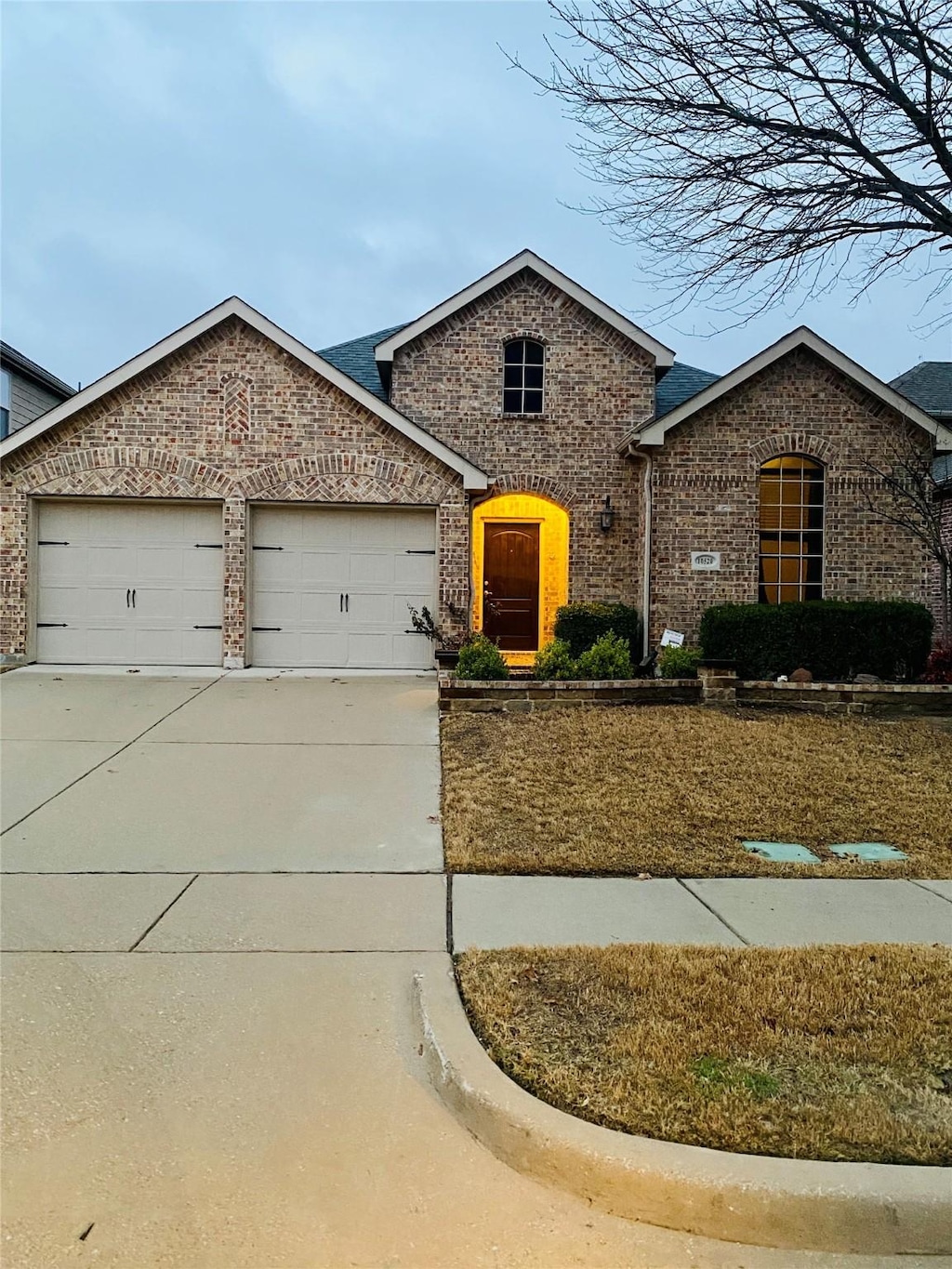 view of front of home featuring brick siding, an attached garage, and concrete driveway