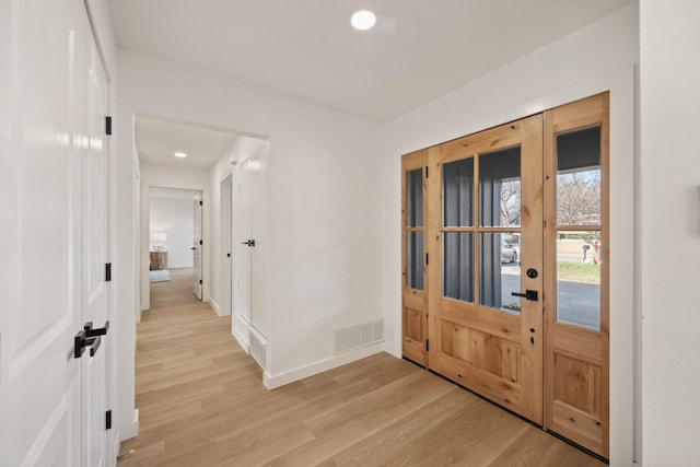 foyer entrance with french doors, baseboards, visible vents, and light wood finished floors