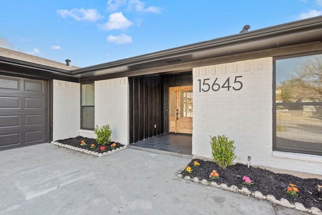 doorway to property with brick siding and an attached garage