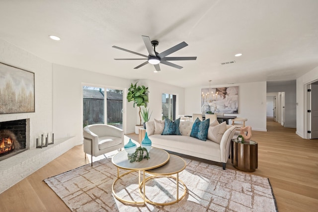 living area with recessed lighting, visible vents, light wood-style floors, and a brick fireplace