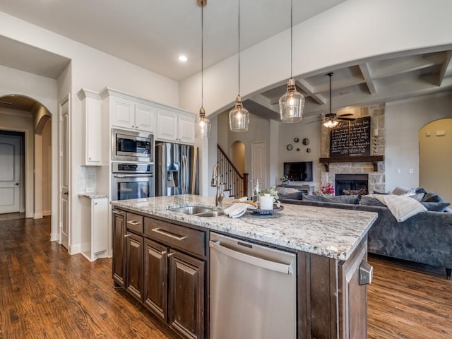 kitchen featuring arched walkways, coffered ceiling, stainless steel appliances, and a sink