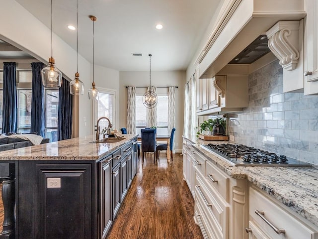 kitchen with light stone countertops, visible vents, dark wood-style flooring, a sink, and stainless steel gas stovetop