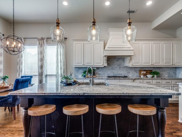 kitchen featuring a sink, visible vents, tasteful backsplash, and white cabinetry