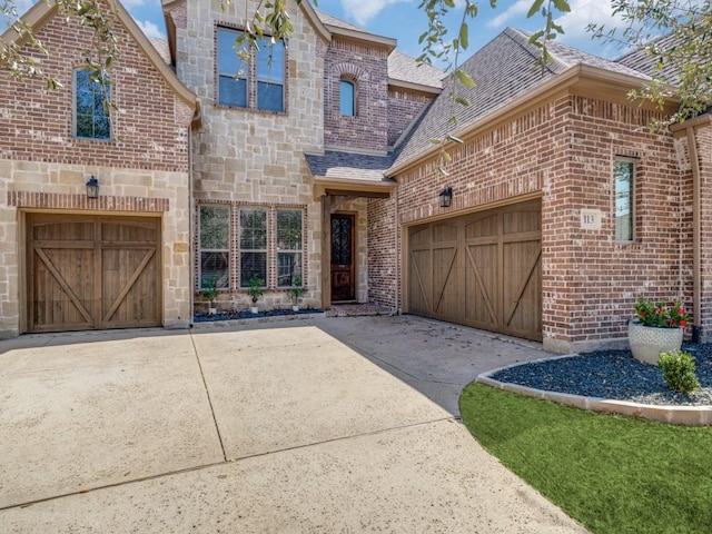 french country home featuring stone siding, brick siding, and concrete driveway