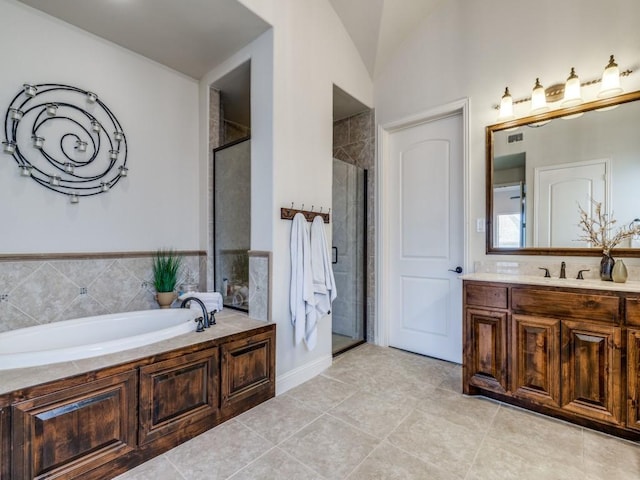 bathroom with a garden tub, a shower stall, tile patterned flooring, lofted ceiling, and vanity