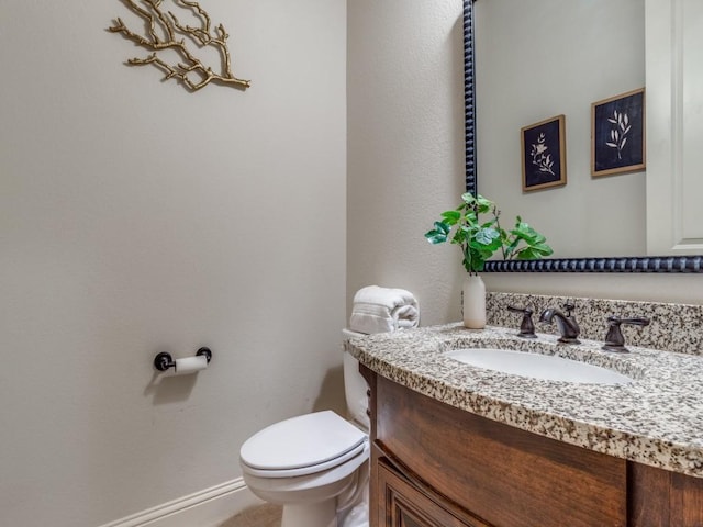 half bath featuring baseboards, toilet, and vanity